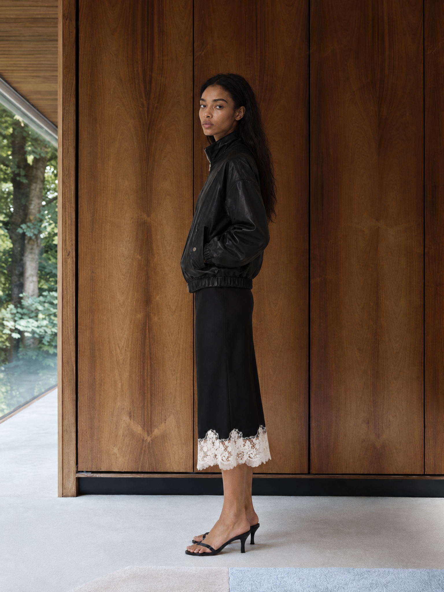 Generated_with_Kive.ai_-_Iora_Black_Shantel_Lace_Trim_Midi_Skirt_Image_1_controls_Iora_s_current_look_and_pose_the_black_leather_bomber_jacket__black_midi_skirt_with_its_white_lace_he.png